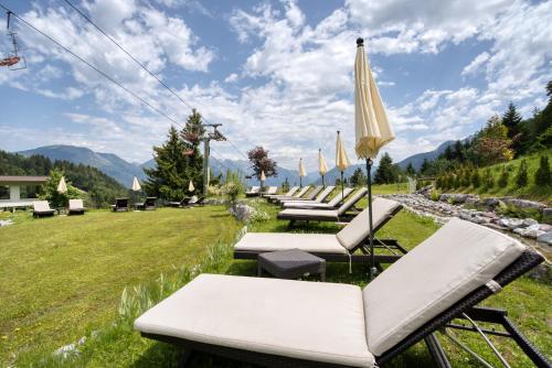 a row of lounge chairs and an umbrella at Alpinresort Schillerkopf in Bürserberg