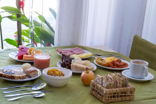 a table with plates of breakfast food on it at Pousada Castelinho in São Sebastião
