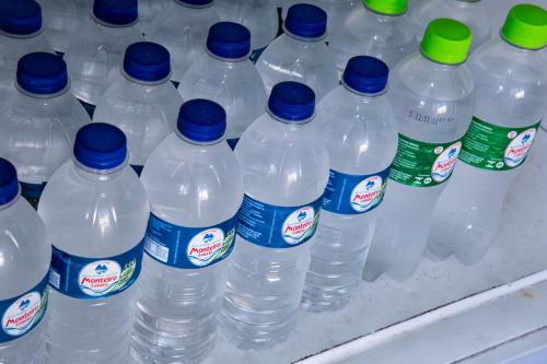 a bunch of water bottles with blue caps on a shelf at Pousada Castelinho in São Sebastião