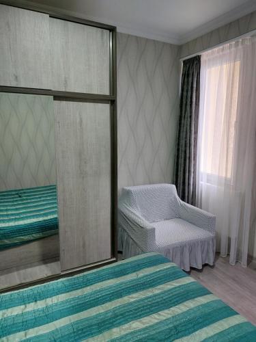 ein Schlafzimmer mit einem Bett, einem Stuhl und einem Spiegel in der Unterkunft Кобулети Residence двухспални Апартаменты Gio in Kobuleti