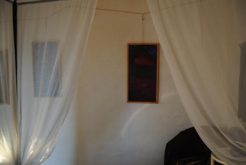 a room with white curtains and a picture on a wall at Case Giannone in Santa Flavia