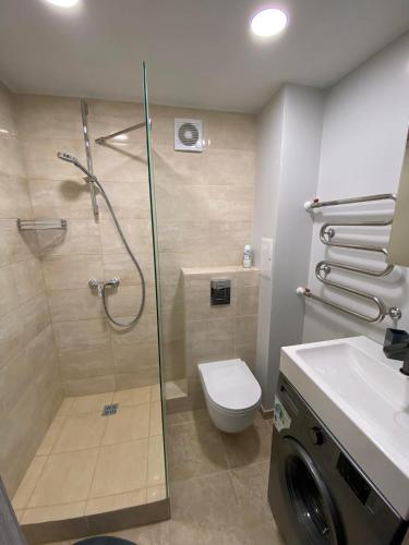 ein Bad mit einer Dusche, einem WC und einem Waschbecken in der Unterkunft ADI Apartamentai in Panevėžys