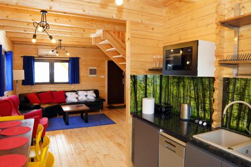 a kitchen and living room in a log cabin at DOM Z SAUNĄ i JACUZZI Bory Tucholskie in Błądzin