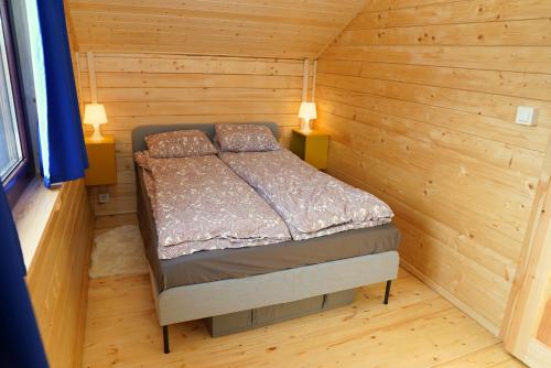a small bedroom with a bed in a log cabin at DOMEK Z SAUNĄ i JACUZZI NAD JEZIOREM BORY TUCHOLSKIE in Błądzin
