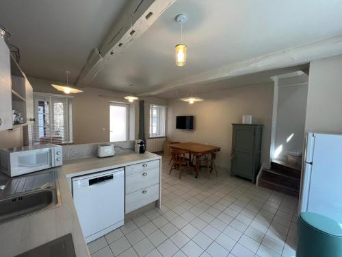 - une cuisine avec des appareils électroménagers blancs et une table dans l'établissement Chez Mauricette, à Saint-Valery-en-Caux