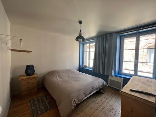 une chambre avec un lit et un bureau et deux fenêtres dans l'établissement Chez Mauricette, à Saint-Valery-en-Caux