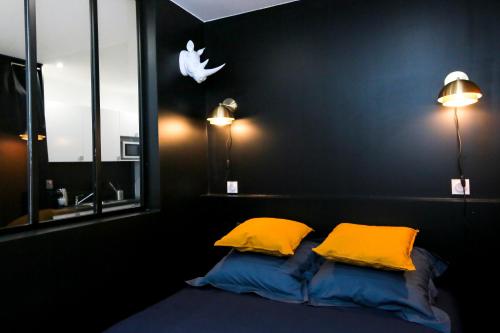 1 dormitorio con 2 almohadas y 1 cama con 2 luces en Le Rhinocéros, T1 hypercentre chic et cosy, Wifi par SOVALFI, en Saint-Étienne