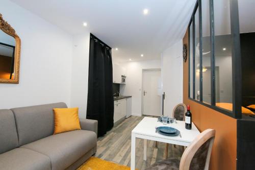 un salon avec un canapé et une table dans l'établissement Le Rhinocéros, T1 hypercentre chic et cosy, Wifi par SOVALFI, à Saint-Étienne