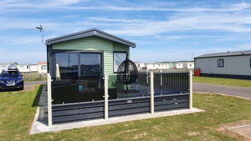 a gazebo with a swing in a yard at 17 Wildflower Meadow in Chapel Saint Leonards