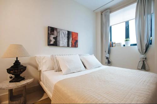 a white bedroom with a bed and a window at Acogedor Apartamento José Laguillo. in Seville