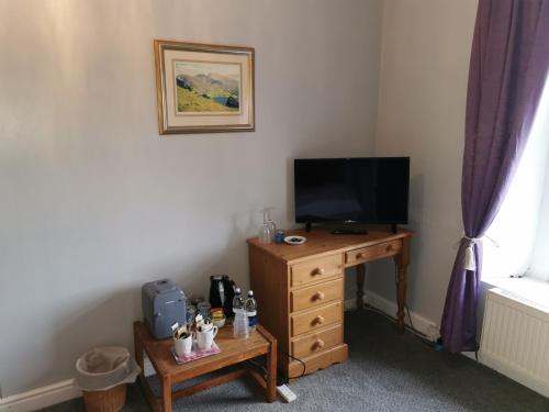 a room with a television and a wooden dresser with a table at Rainors farm B&B in Gosforth