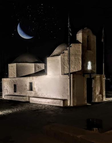 a night view of a building with a moon in the sky at Άνετο διαμέρισμα στο κέντρο της πόλης in Aegina Town