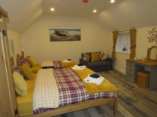 a bedroom with two beds and a couch at The Stables At Eastmoor Farm in Bridlington