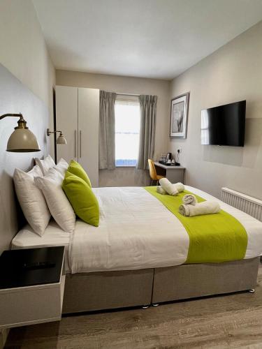 a bedroom with a large bed with green and white pillows at Pearl & Pebbles Eastbourne in Eastbourne