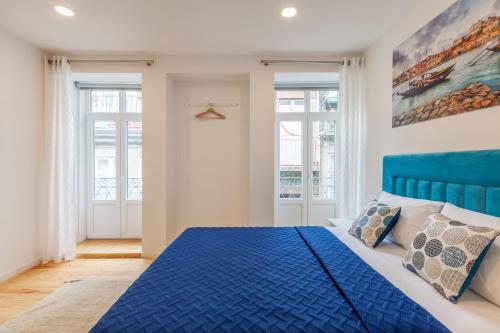 ポルトにあるVilla Apartments & Suitesの青いベッドと2つの窓がある寝室