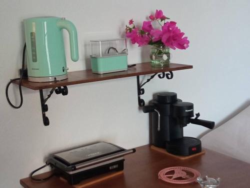 a shelf on a wall with a coffee maker and flowers at Estia κατάλυμα στο Μύρτος in Myrtos