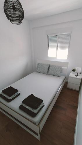 a white bed in a room with two windows at Apartamento Aguilera in Gandía