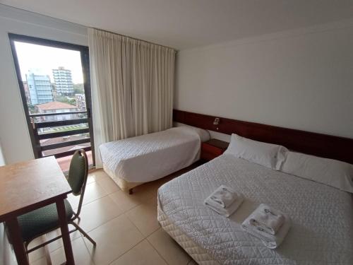 um quarto de hotel com duas camas e uma mesa e uma janela em Intersur Villa Gesell em Villa Gesell