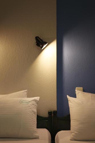 a room with two beds and a light on the wall at Anesis Hotel in Agios Ioannis Pelio