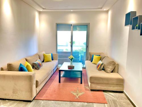 a living room with two couches and a table at Bel Appartement à AMWAJ Beach and Resorts in Casablanca