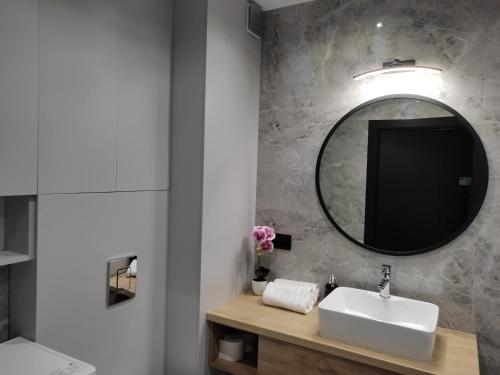 a bathroom with a sink and a mirror at Apartament Zamkowe Wzgórze in Lidzbark Warmiński