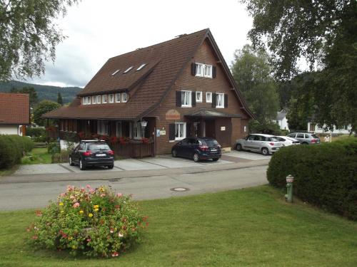 dom z samochodami zaparkowanymi przed nim w obiekcie Pension Bergseeblick w mieście Titisee-Neustadt