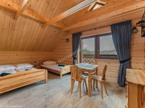 a log cabin bedroom with a table and two beds at Nurt Food Uroczysko Jaworki in Jaworki