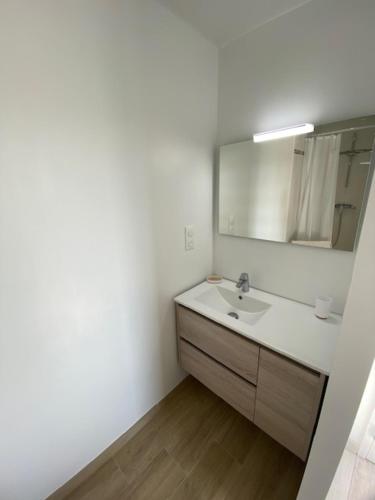 une salle de bain blanche avec un lavabo et un miroir dans l'établissement Chambre d'hôtes près de la plage, à Pornichet