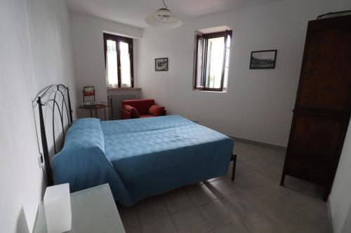 1 dormitorio con 1 cama azul y 1 silla en Appartamento in borgata storica, en Boissano