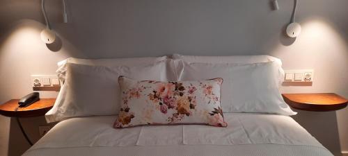 a bed with white sheets and a pillow on it at Hotel Oleum - Parking Gratuito Reserva Previa in Andújar
