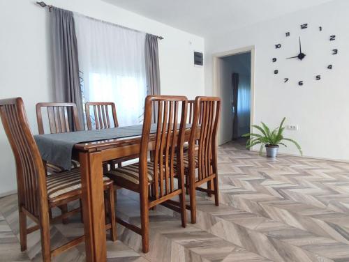 Una mesa de comedor con sillas y un reloj en la pared. en Apartman Flora Vrdnik, en Vrdnik