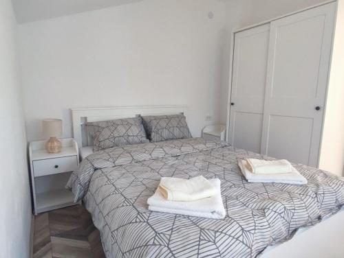 a white bedroom with a bed with two towels on it at Apartman Flora Vrdnik in Vrdnik