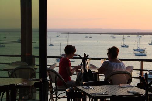 two women sitting at tables in a restaurant looking at the water at Seven Crown La Paz Malecon in La Paz