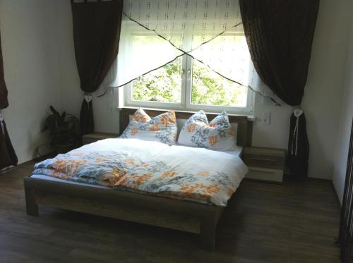 Bett in einem Schlafzimmer mit einem Fenster mit Vorhängen in der Unterkunft Harmonie Stüberl in Ottnang am Hausruck