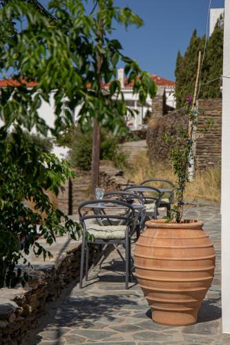 a group of chairs and a large vase with a plant in it at Korina's Suites in Andros