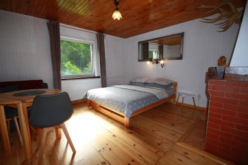 Schlafzimmer mit einem Bett, einem Tisch und einem Fenster in der Unterkunft Białowieska Leśniczówka "U Jasia i Małgosi" in Czerlonka