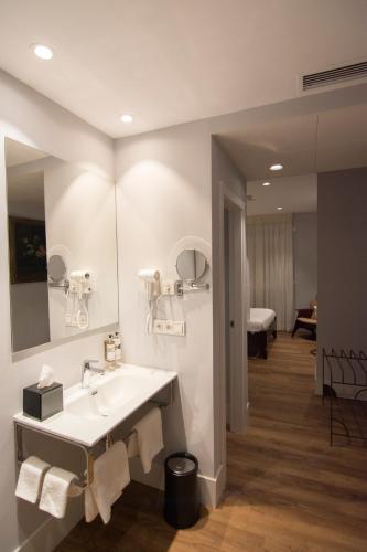 a white bathroom with a sink and a mirror at Hotel Oleum - Parking Gratuito Reserva Previa in Andújar