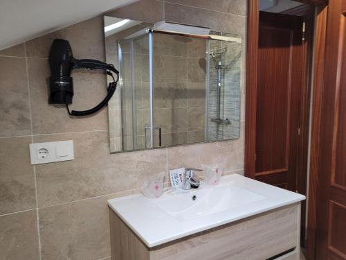 a bathroom with a white sink and a mirror at Hotel Restaurante el Fornon in Novellana