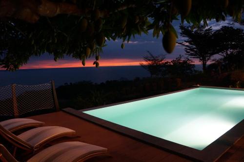 a swimming pool with two chairs and a sunset at VILLA DOMINGO - Incroyable vue panoramique in Andilana