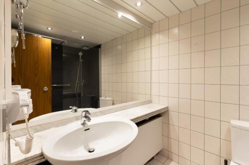 ein weißes Badezimmer mit einem Waschbecken und einem Spiegel in der Unterkunft GelsenDesign III - Netflix I Balkon I Zentral in Gelsenkirchen