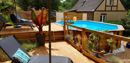 una terraza de madera con piscina y una casa en Le Vieux Moulin Gites - A charming stone cottage with garden view and seasonal pool, en Guégon