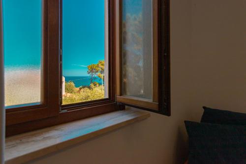 a room with a window with a view of the beach at Hotel Baia Del Capitano in Cefalù