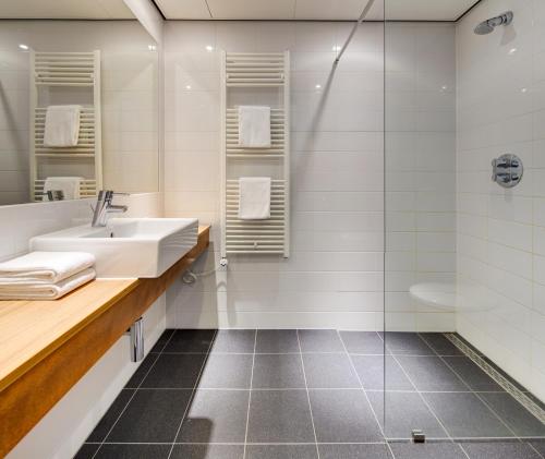 uma casa de banho com um lavatório e um chuveiro em Fletcher Hotel-Restaurant Mooi Veluwe em Putten