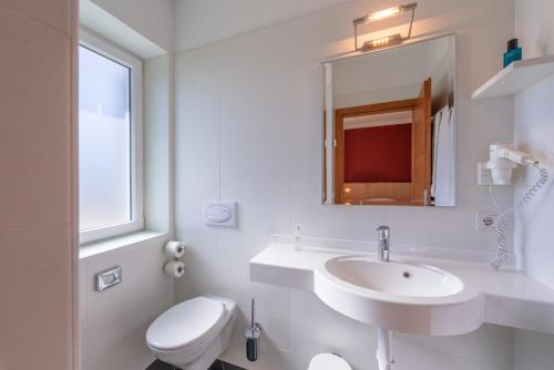 a white bathroom with a sink and a toilet at Sandhof Ferienwohnungen in Termeno