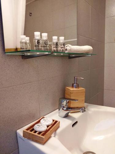 a bathroom sink with a mirror and a shelf above it at LAGADA HOLIDAY ROOMS in Lagkáda