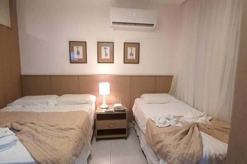 2 camas en una habitación con una lámpara en una mesa en Solar Água Pipa - Apto 115, en Pipa