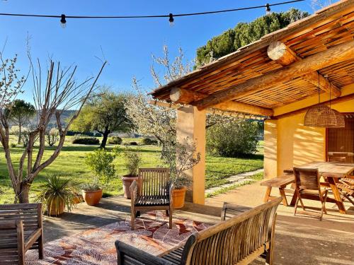 eine Terrasse mit Holzbänken, einem Tisch und einem Picknicktisch in der Unterkunft Domaine de la Bastidonne in Céreste