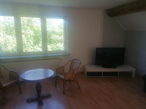 a living room with a table and chairs and a television at Gästehaus an der Warnow in Schwaan