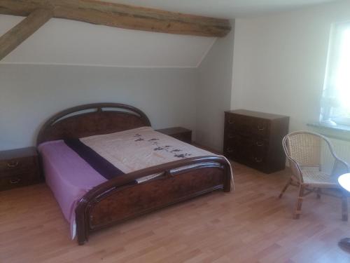 a bedroom with a wooden bed and a chair at Gästehaus an der Warnow in Schwaan