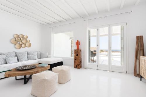 Sala de estar blanca con sofá y mesa en Villa Iliada, en Playa de Elia